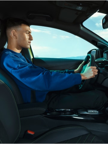 Mann in der Fahrposition des PEUGEOT E-208
