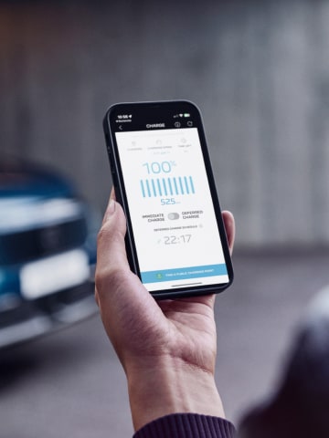 Frau mit Smartphone vor dem PEUGEOT E-3008 Dual Motor