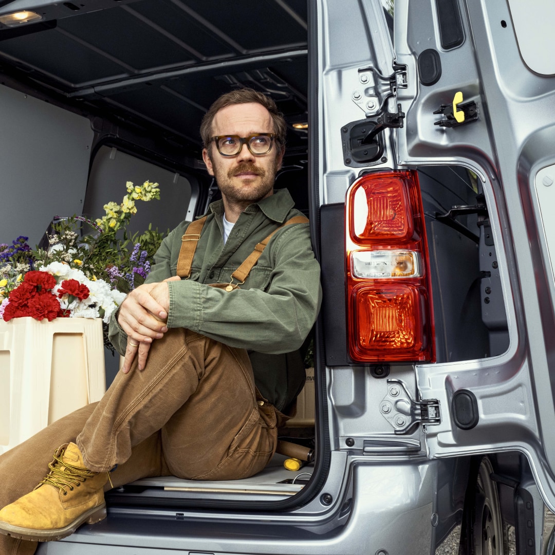 Heckansicht des PEUGEOT E-Expert mit geöffneten Hecktüren und einer Person am Fahrzeugheck