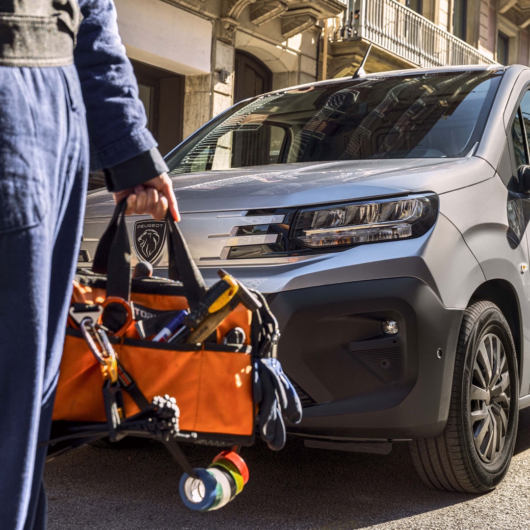 Frau steht vor einem PEUGEOT E-Partner
