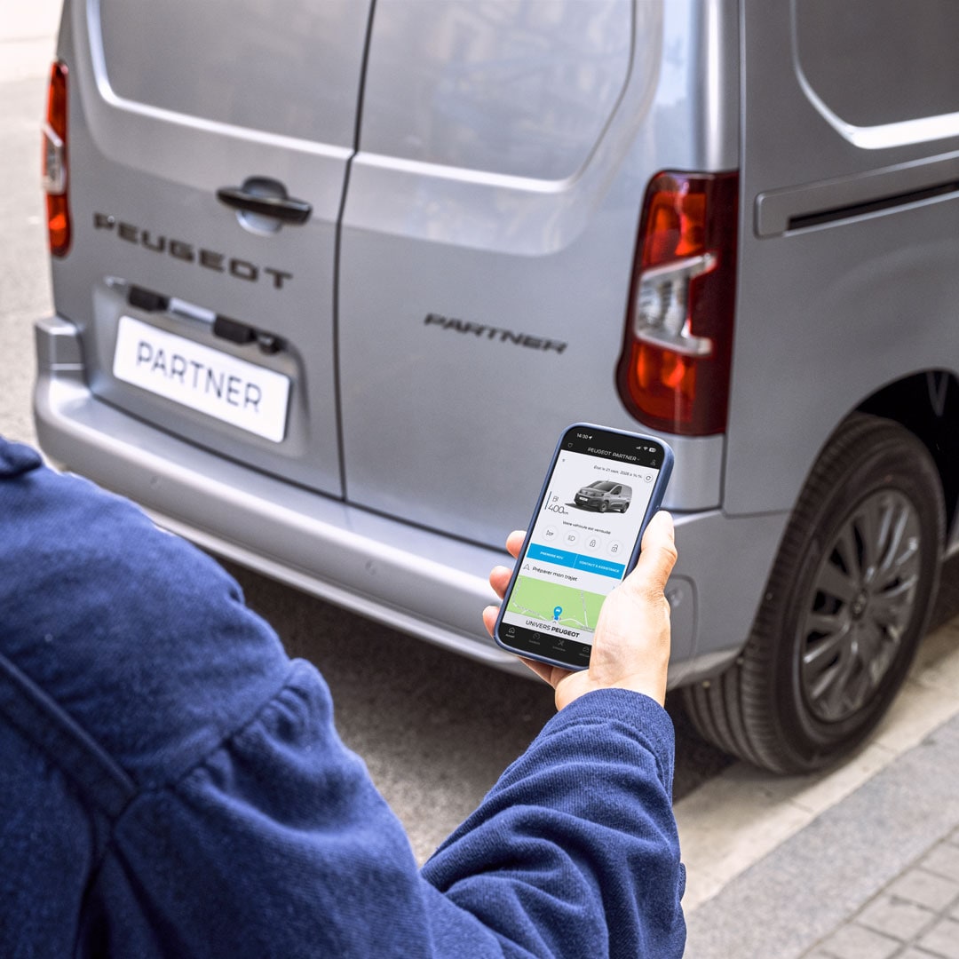Woman using a smartphone behind the PEUGEOT Partner
